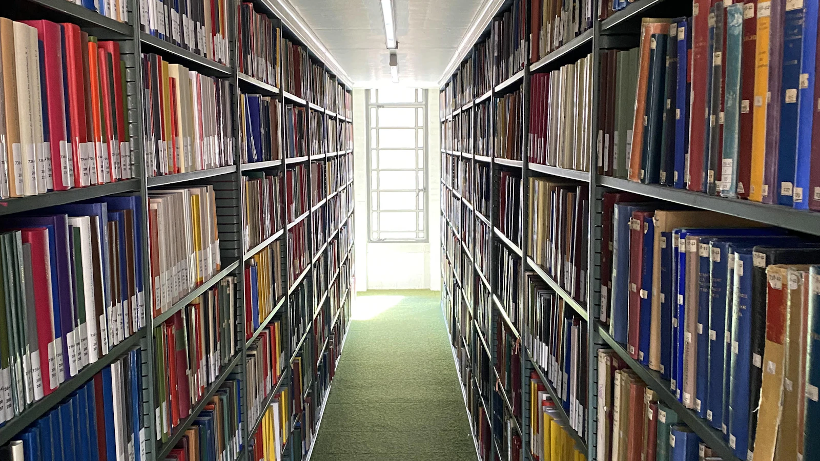 Pasillo de una biblioteca con estanterías de libros a ambos lados.